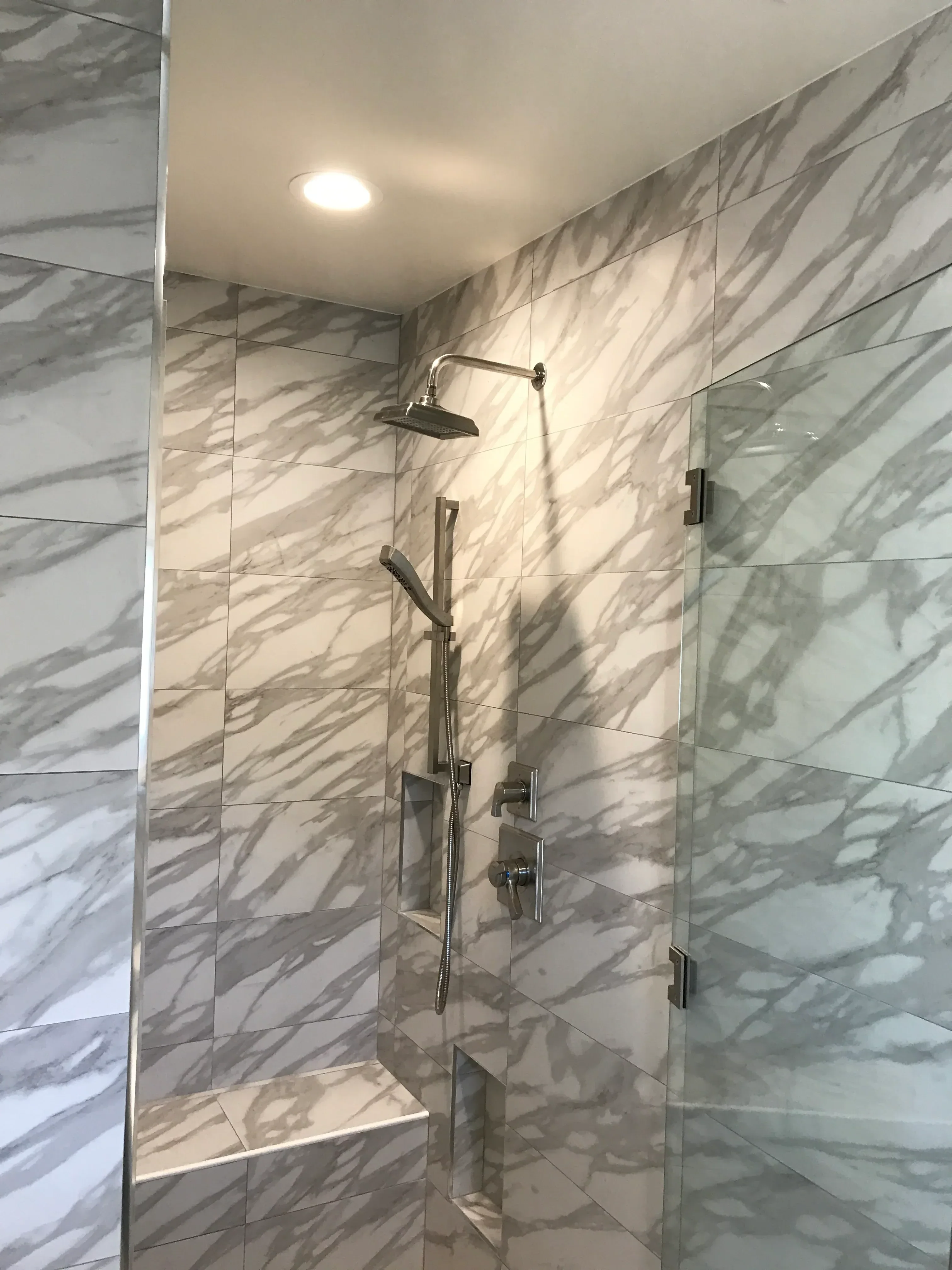 Marble tile shower with chrome fixtures and recessed lighting