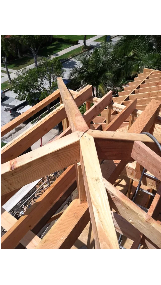 Wooden roof framing with dimensional lumber beams, rafters, and trusses during construction